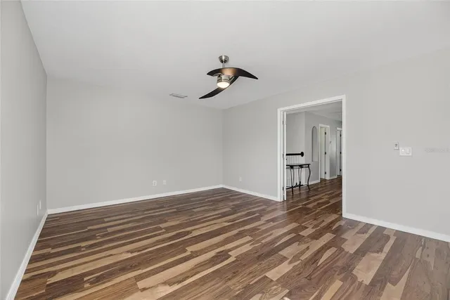 an empty room with a chandelier fan and windows