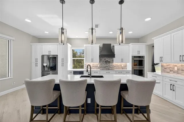 a large kitchen with kitchen island a large counter space a sink a window and stainless steel appliances