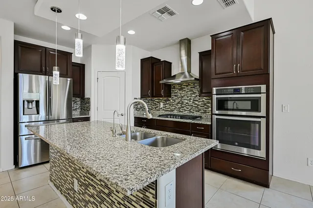 a kitchen with stainless steel appliances kitchen island granite countertop a refrigerator and stove