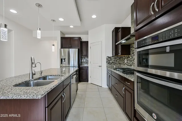 a kitchen with stainless steel appliances granite countertop a sink a stove and a refrigerator