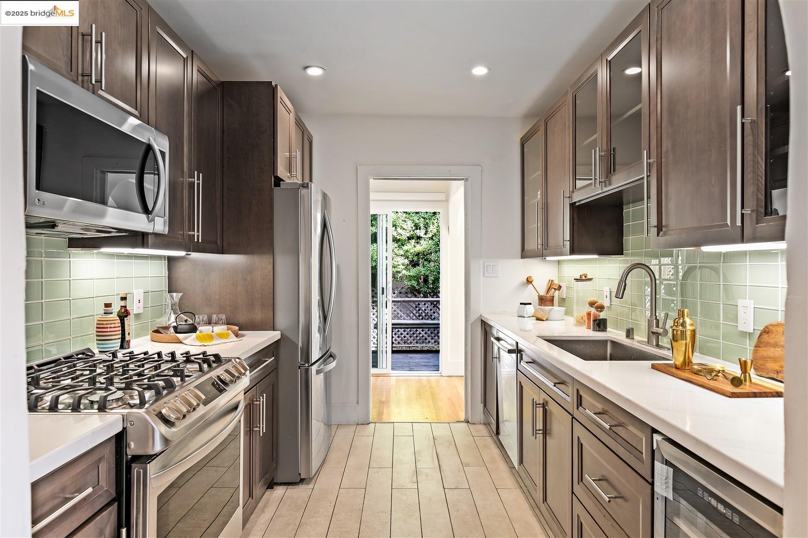 2201-2203 Spaulding Avenue Berkeley, CA 94703 - Photo 14 of 56 Kitchen with tasteful backsplash, glass insert cabinets, appliances with stainless steel finishes, dark brown cabinets, and recessed lighting