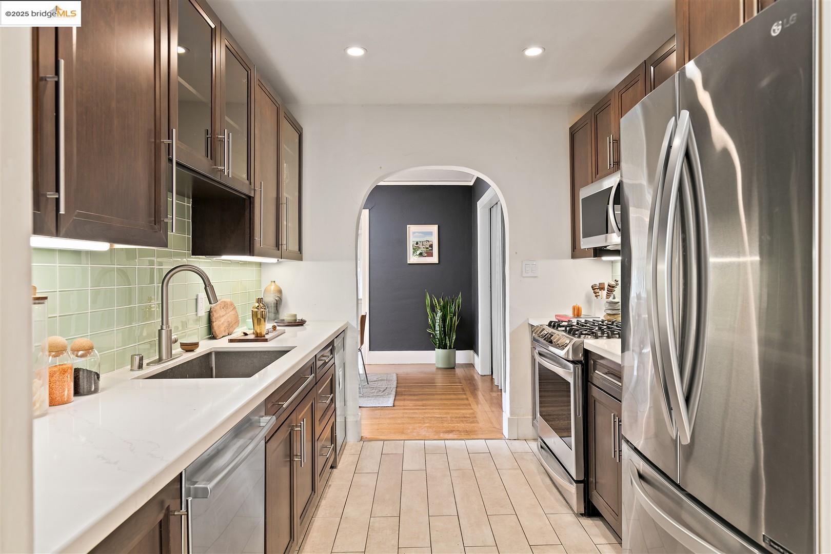 2201-2203 Spaulding Avenue Berkeley, CA 94703 - Photo 15 of 56 Kitchen featuring glass insert cabinets, appliances with stainless steel finishes, arched walkways, recessed lighting, and dark brown cabinets