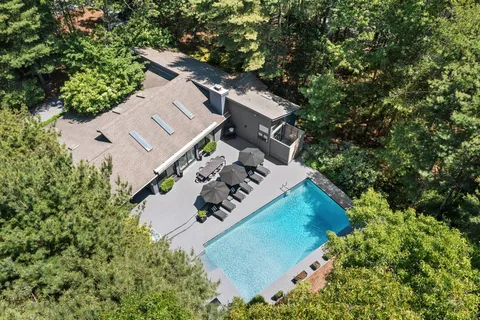 an aerial view of a house with a yard and trees all around