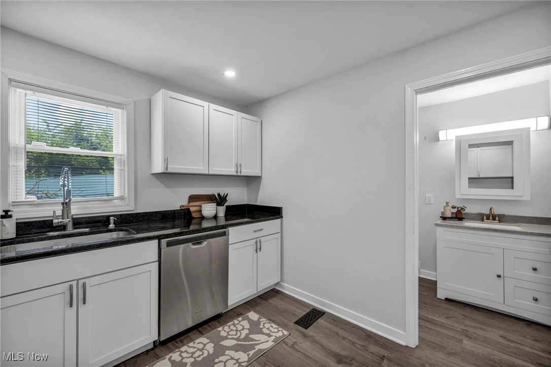 4649 Burleigh Road Cleveland, OH 44125 - Photo 21 of 37 Kitchen featuring dark stone countertops, white cabinetry, stainless steel dishwasher, dark wood finished floors, and recessed lighting