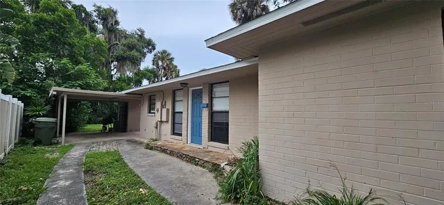 a view of a house with brick walls plants and large tree