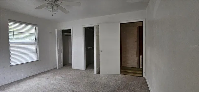 an empty room with a ceiling fan and a window