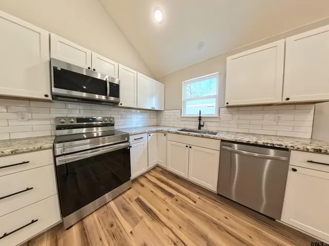 a kitchen with stainless steel appliances granite countertop a sink a stove a microwave and cabinets