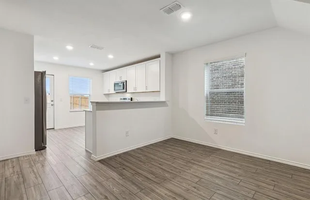 a view of a kitchen with wooden floor and electronic appliances