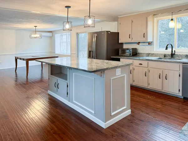 a kitchen with stainless steel appliances granite countertop wooden floors and white cabinets