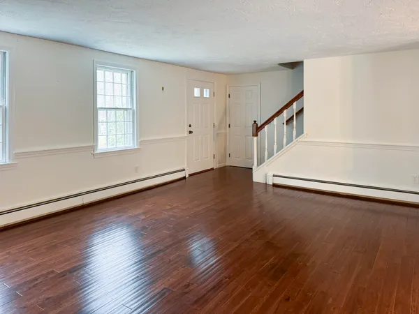 an empty room with wooden floor and windows