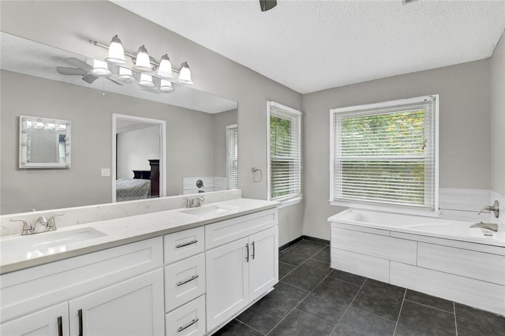 2610 Loring Road Northwest Kennesaw, GA 30152 - Photo 16 of 28 a spacious bathroom with a granite countertop sink a large mirror a bathtub and next to a window