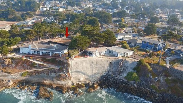 an aerial view of ocean and residential houses with outdoor space