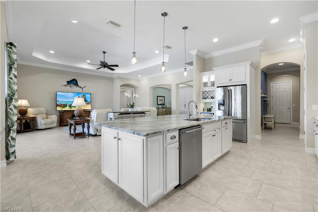 1456 Mockingbird Drive Naples, FL 34120 - Photo 43 of 43 Kitchen featuring arched walkways, white cabinetry, appliances with stainless steel finishes, open floor plan, and hanging light fixtures