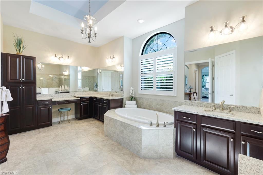 1456 Mockingbird Drive Naples, FL 34120 - Photo 22 of 43 Bathroom featuring two vanities, a garden tub, a chandelier, and light tile patterned floors