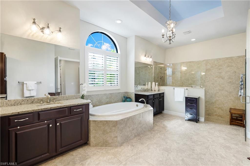 1456 Mockingbird Drive Naples, FL 34120 - Photo 23 of 43 Full bath featuring a bath, a walk in shower, two vanities, light tile patterned floors, and a chandelier