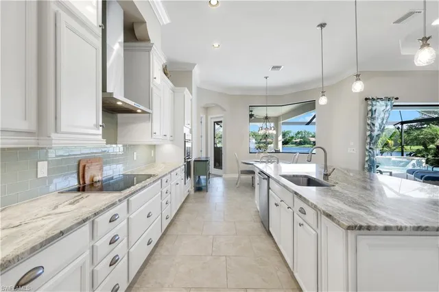 a large white kitchen with granite countertop lots of counter space and a sink
