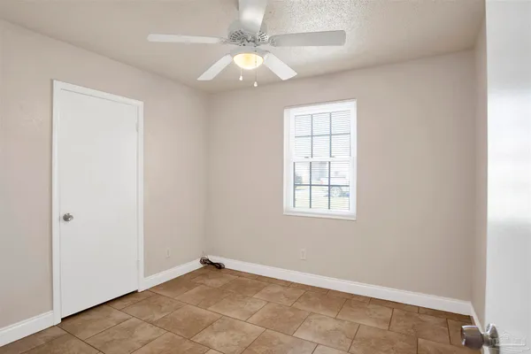 an empty room with windows and fan