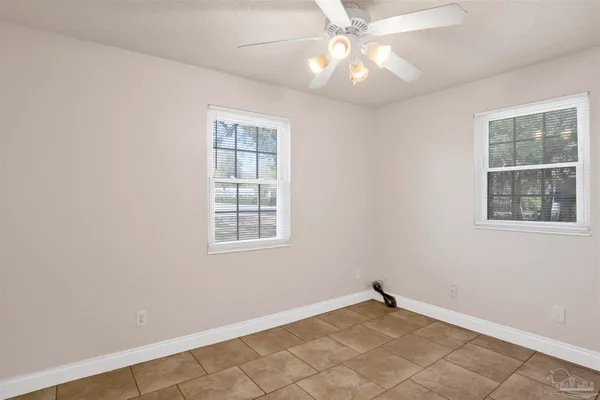 an empty room with chandelier fan and windows