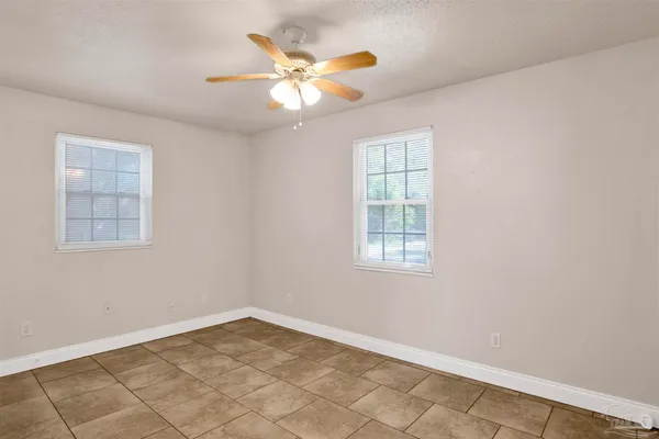 an empty room with windows and fan