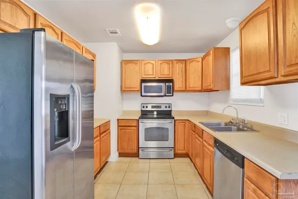 a kitchen with granite countertop a sink a counter top space stainless steel appliances and cabinets