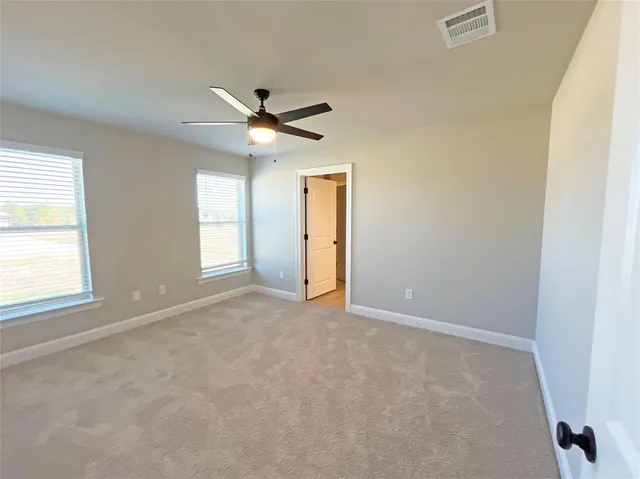 an empty room with windows and fan