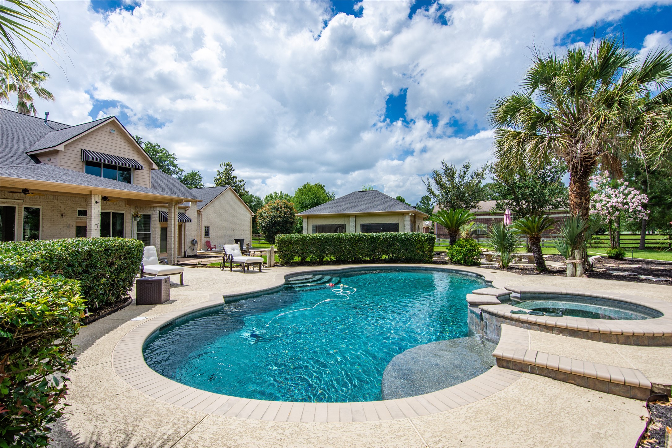 13914 Skinner Road Cypress, TX 77429 - Photo 45 of 50 Curved pool framed by tropical landscaping, with a raised spa and plenty of surrounding patio space for lounging.