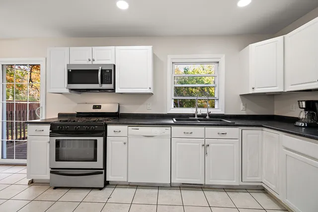 a kitchen with white cabinets appliances and a window