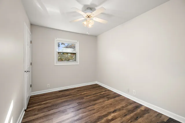 an empty room with a window and a fan