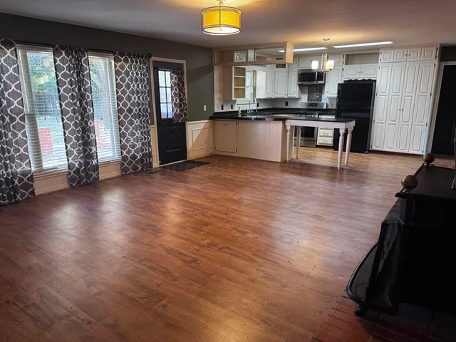 an open kitchen with wooden floor and stainless steel appliances