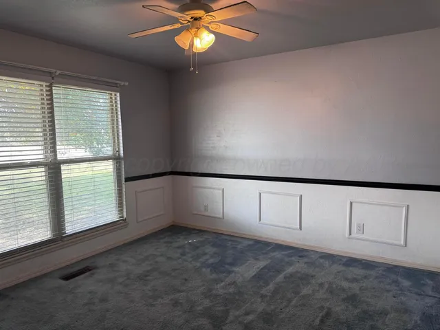 an empty room with windows and chandelier fan