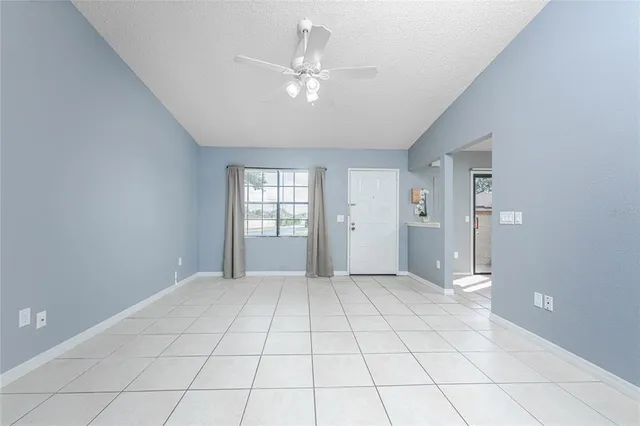a view of an empty room with window and chandelier fan