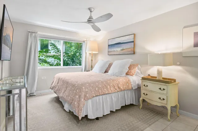 a bedroom with a bed next to a large window with a dresser