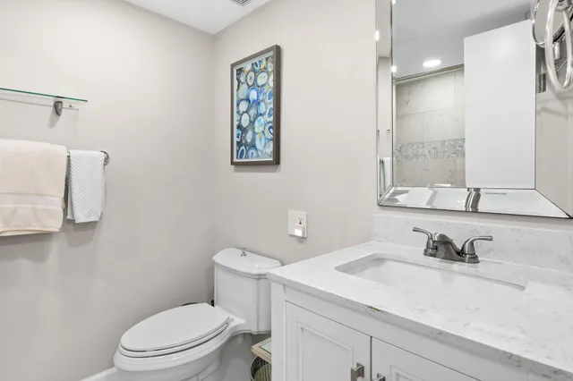a bathroom with a granite countertop sink mirror vanity and toilet
