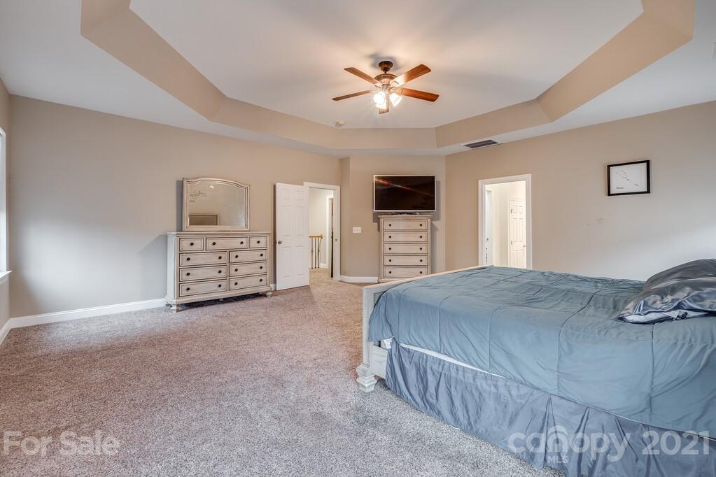 415 Fischer Road Fort Mill, SC 29715 - Photo 22 of 48 a spacious bedroom with a bed and a chandelier