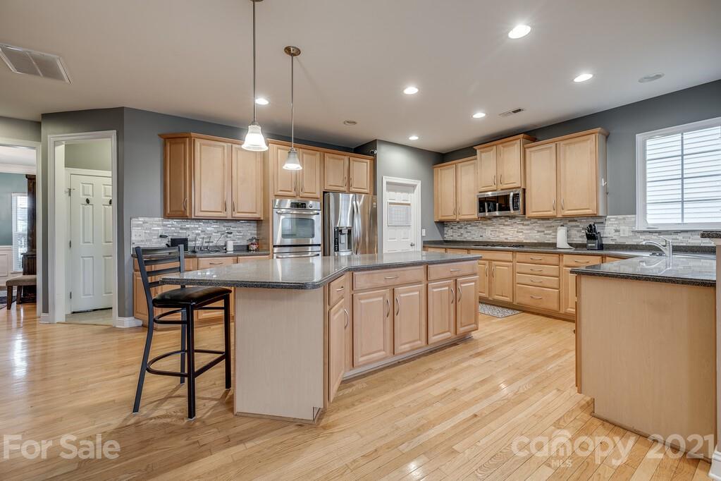 415 Fischer Road Fort Mill, SC 29715 - Photo 10 of 48 a kitchen with stainless steel appliances kitchen island granite countertop a stove a sink a refrigerator and white cabinets with wooden floor
