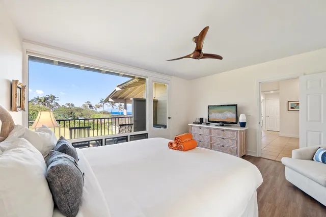 a bedroom with a bed a large window and flat screen tv