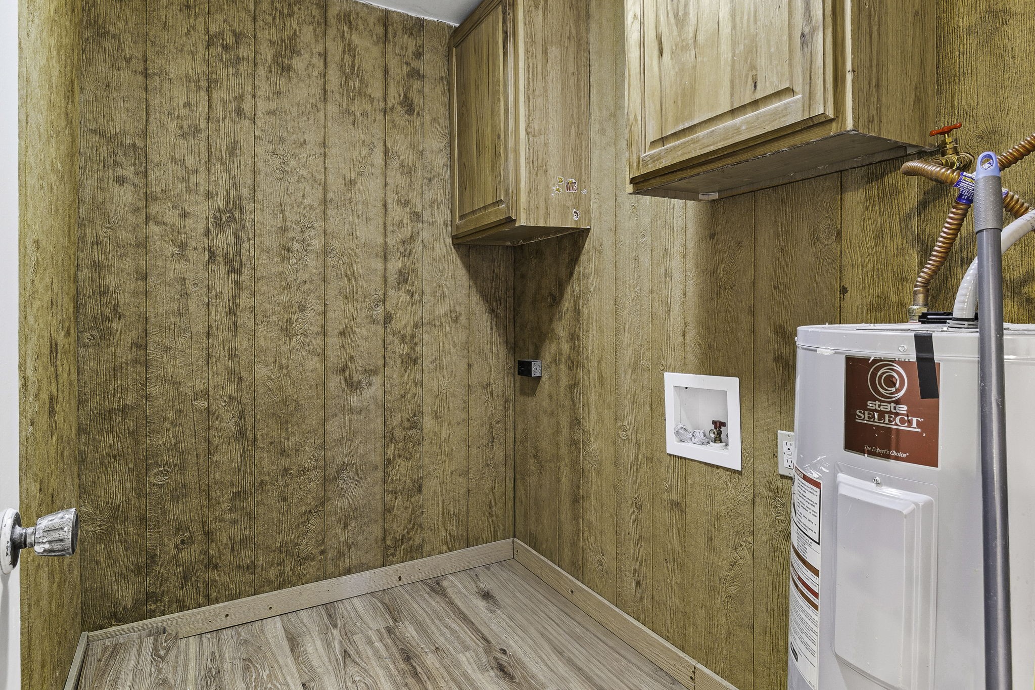 Cozy utility room with wood paneling, ample storage cabinets, and a modern water heater.