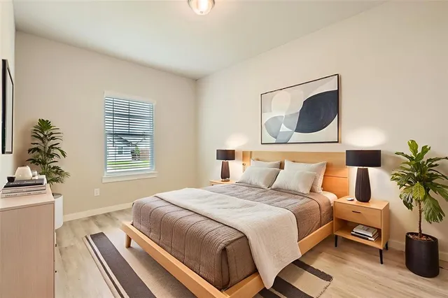 a bedroom with a bed and a potted plant on the dresser
