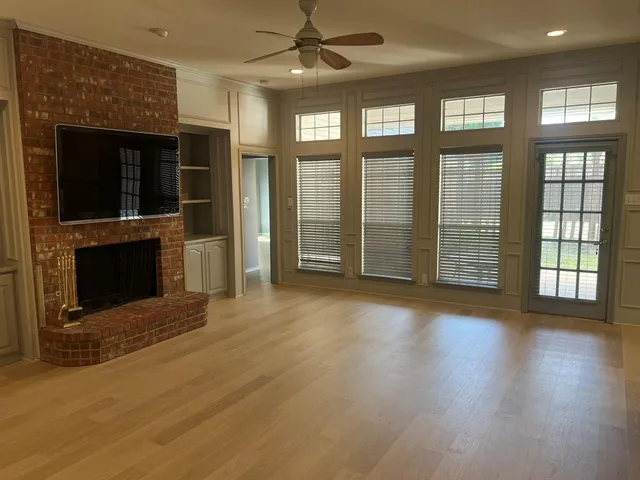 a view of an empty room with wooden floor and a fireplace