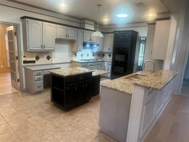 a kitchen with kitchen island granite countertop wooden cabinets and a stainless steel appliances