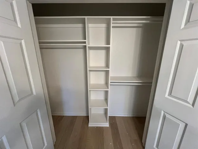 a view of walk in closet with wooden floor