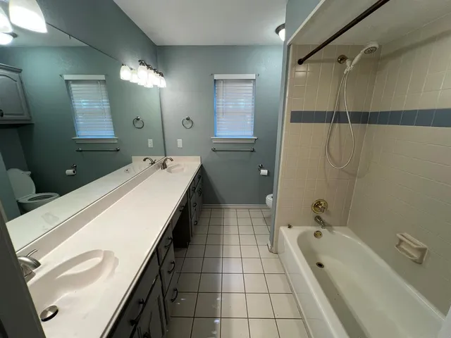 a spacious bathroom with a granite countertop sink a mirror and a bathtub