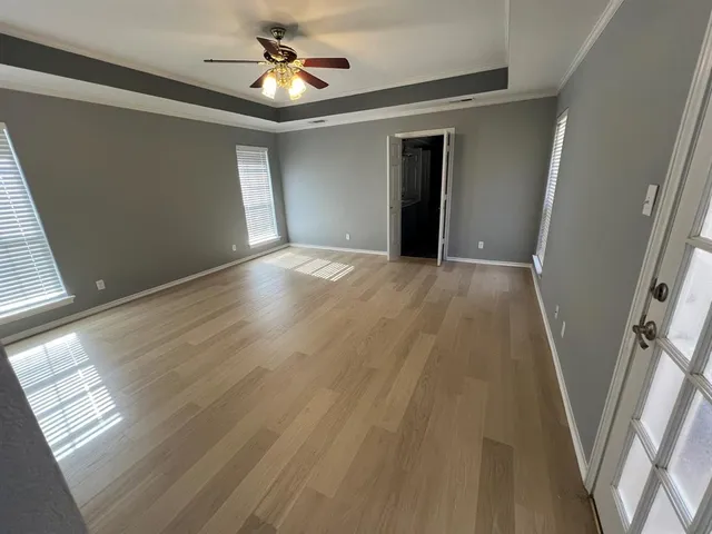 a view of empty room with wooden floor and fan