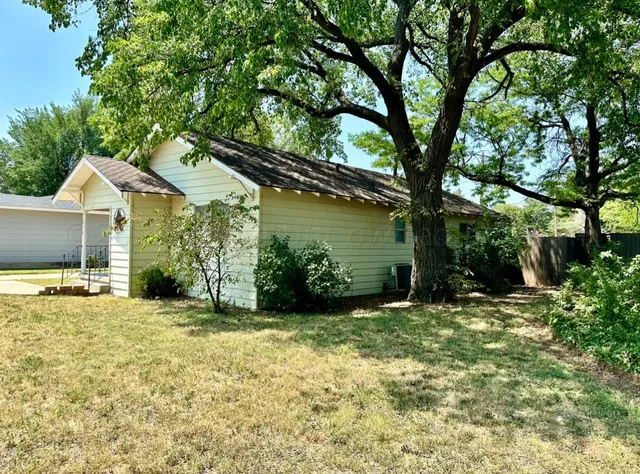 a view of a house with a yard and large tree