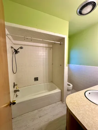 a bathroom with a granite countertop sink a toilet and shower