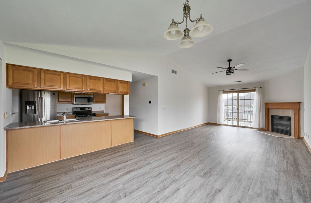 962 Arvle Circle, Unit 962 Sycamore, IL 60178 - Photo 5 of 18 a open kitchen with granite countertop a stove top oven a sink dishwasher and a fireplace with wooden floor