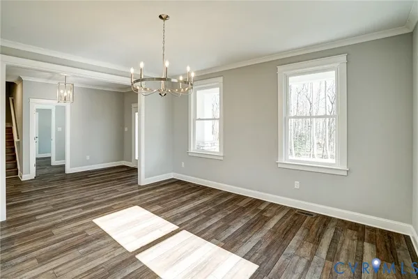 a view of an empty room with wooden floor fridge and a window
