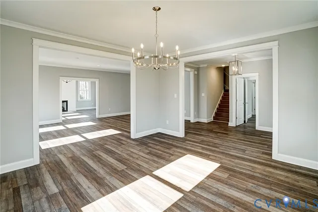 a view of an empty room with wooden floor and a kitchen