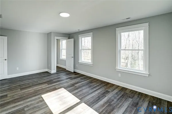 a view of an empty room with wooden floor and window
