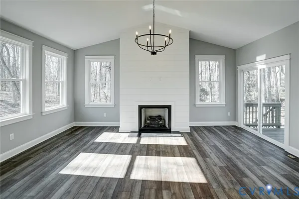 a view of an empty room with wooden floor fireplace and a window